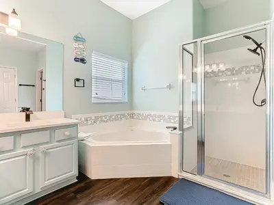 a white bathroom with a tub and a shower at Group retreat w pool, spa & BBQ in Orlando