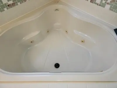a white bath tub sitting in a bathroom at Group retreat w pool, spa & BBQ in Orlando