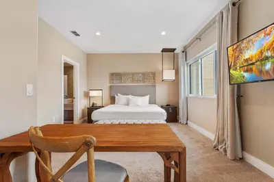 a bedroom with a bed and a desk and a tv at Minutes to Disney Chic Dream Villa with Stunning Patio and Resort Perks in Orlando