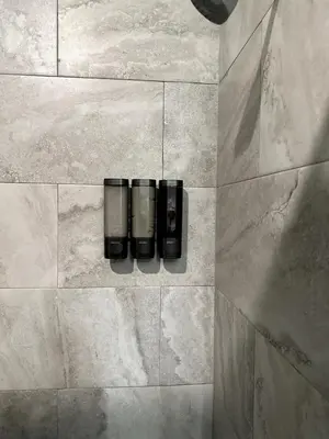 a shower with three black bottles on a tile wall at Carri-Vision Suite in Kissimmee