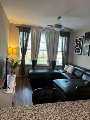 a living room with a black leather couch and windows at Carri-Vision Suite in Kissimmee