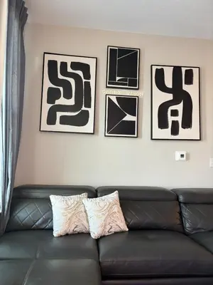 a black couch in a living room with pictures on the wall at Carri-Vision Suite in Kissimmee