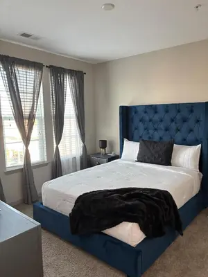 a bedroom with a large bed with a blue headboard at Carri-Vision Suite in Kissimmee