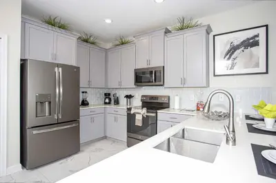 a kitchen with white cabinets and a stainless steel refrigerator at Epic Dream Home with Spa Game Room Themed Bedrooms 2887 Single Family in Kissimmee