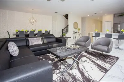 a living room with a black couch and a table at Epic Dream Home with Spa Game Room Themed Bedrooms 2887 Single Family in Kissimmee