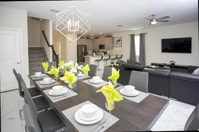 a dining room and living room with a table with yellow flowers at Epic Dream Home with Spa Game Room Themed Bedrooms 2887 Single Family in Kissimmee