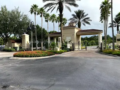 a house with a gate and palm trees at Vacation Villa Near Disney With Private Pool Spa in Kissimmee