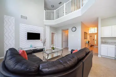 a living room with a leather couch and a tv at Vacation Villa Near Disney With Private Pool Spa in Kissimmee