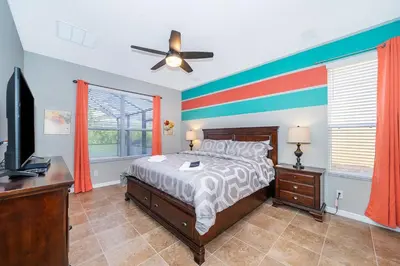 a bedroom with a bed with a colorful accent wall at Vacation Villa Near Disney With Private Pool Spa in Kissimmee