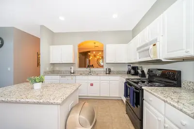 a kitchen with white cabinets and a stove top oven at Vacation Villa Near Disney With Private Pool Spa in Kissimmee
