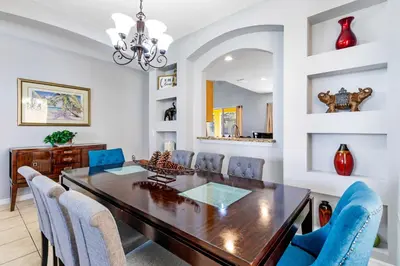 a dining room with a wooden table and blue chairs at Disney Doorstep 7 Bedroom Villa with SouthFacing Pool and Hot Tub in Kissimmee