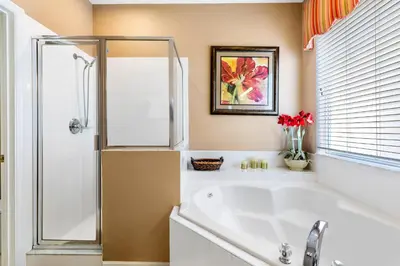 a bathroom with a tub and a glass shower at Disney Doorstep 7 Bedroom Villa with SouthFacing Pool and Hot Tub in Kissimmee