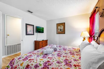 a bedroom with a bed with a floral bedspread at Disney Doorstep 7 Bedroom Villa with SouthFacing Pool and Hot Tub in Kissimmee