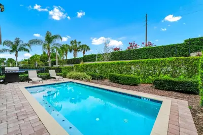 a swimming pool in a yard with two chairs and a table at Welcoming Home With Game Room And Private Pool With Water Park Access At Encore Resorts Reunion - 150Mn in Kissimmee