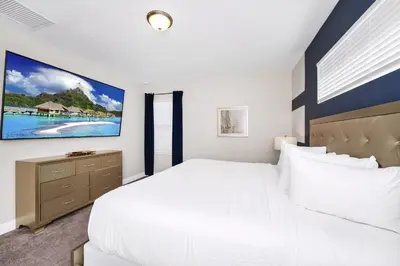 a white bedroom with a large bed and a tv at Marvelous Home With Media Room, Theme Room And Waterpark & Resort Access Near Disney At Encore Resorts Reunion - 7485Mr in Kissimmee