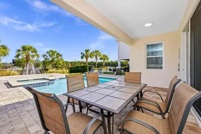 a patio with a table and chairs and a swimming pool at Marvelous Home With Media Room, Theme Room And Waterpark & Resort Access Near Disney At Encore Resorts Reunion - 7485Mr in Kissimmee