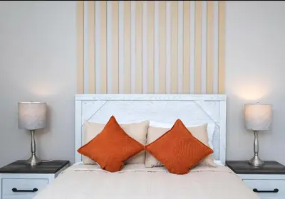 a bedroom with a white bed with orange pillows at Amazing Townhome With Lake View At Storey Lake Resort in Kissimmee