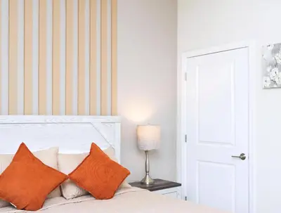 a bedroom with a white bed with orange pillows at Amazing Townhome With Lake View At Storey Lake Resort in Kissimmee