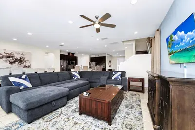 a living room with a blue couch and a ceiling fan at Extravagant Home With Movie Theater, Private Pool And Waterpark & Resort Access At Encore Resort - 241Fl in Kissimmee