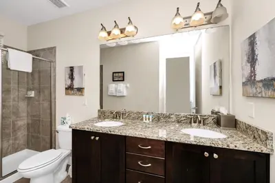 a bathroom with two sinks and a toilet and a mirror at Extravagant Home With Movie Theater, Private Pool And Waterpark & Resort Access At Encore Resort - 241Fl in Kissimmee