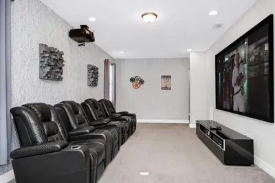 a living room with black leather chairs and a flat screen tv at Magnificent Home With Private Pool, Theater & Game Room Near Disney With Waterpark & Resort Access At Encore Resort - 230Bu in Kissimmee