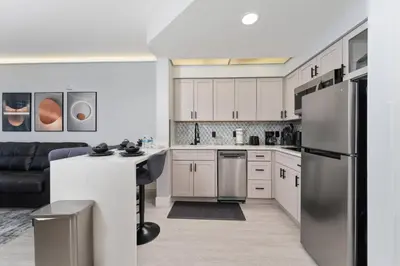 a kitchen with white cabinets and a stainless steel refrigerator at Spacious 1BR near Universal I-Drive in Orlando