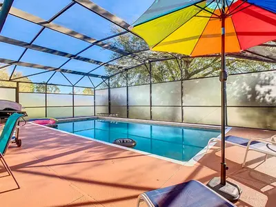 a colorful umbrella sitting next to a swimming pool at 4BR home w pool, spa & BBQ grill in Orlando