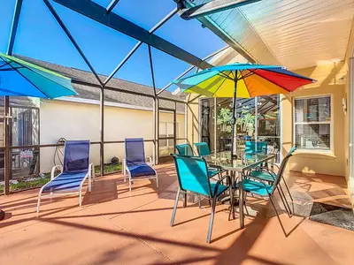 a patio with a table and chairs and umbrellas at 4BR home w pool, spa & BBQ grill in Orlando
