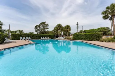 a large swimming pool with chairs and trees at 9 min to Disney Entrance-Peaceful Single Family House in Kissimmee