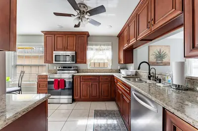 a kitchen with wooden cabinets and a ceiling fan at 9 min to Disney Entrance-Peaceful Single Family House in Kissimmee