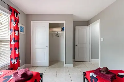 a bedroom with two beds and a red curtain at 9 min to Disney Entrance-Peaceful Single Family House in Kissimmee