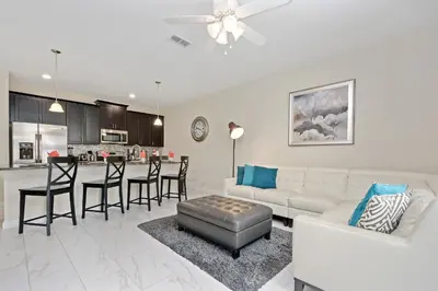 a living room with a white couch and a kitchen at Wonderful 4Bd with Pool at Storey Lake Resort 4819 in Kissimmee