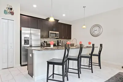 a kitchen with a bar with four chairs at a counter at Wonderful 4Bd with Pool at Storey Lake Resort 4819 in Kissimmee