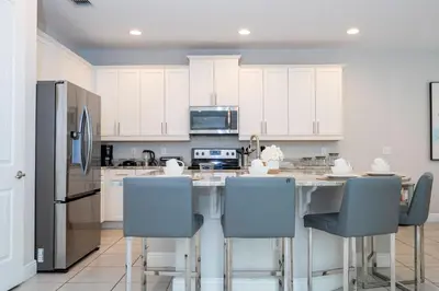 a kitchen with white cabinets and a table with chairs at Fantastic 5BR Villa Near Disney - Priv. Pool SPA in Orlando