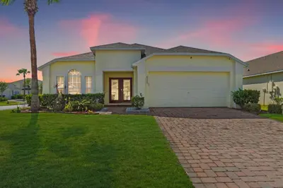a house with a garage and a palm tree at NEW King Bed Glow In The Dark Kid Cave in Kissimmee