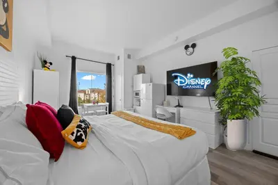 a bedroom with a large white bed and a tv at King Bed Theme Park Hotel Free Shuttle Included in Orlando