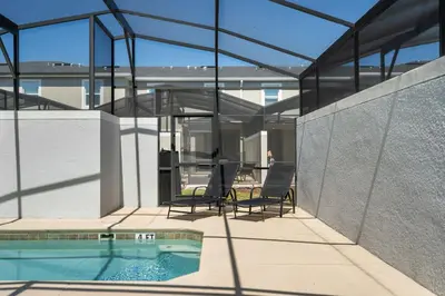 a glass house with a swimming pool and two chairs at Stylish 4BR home Near Disney with Themed Rooms in Kissimmee