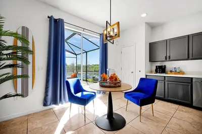 a kitchen with a table and two blue chairs at Lilo & Stitch Themed Villa 10 Min to Disney! Heated Pool & Game Room in Orlando