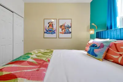 a bedroom with a bed and some pictures on the wall at Lilo & Stitch Themed Villa 10 Min to Disney! Heated Pool & Game Room in Orlando