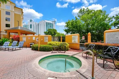 a hot tub in a courtyard with chairs and a building at Unit near Epic Universe and Universal Studios - free parking in Orlando
