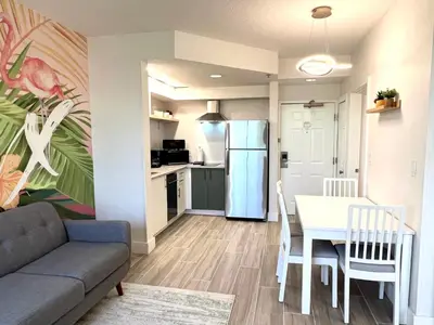 a living room with a table and a kitchen with a refrigerator at Unit near Epic Universe and Universal Studios - free parking in Orlando