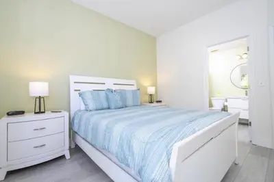 a white bedroom with a white bed and two night stands at Sunshine Escape 20 minutes from Disney in Kissimmee