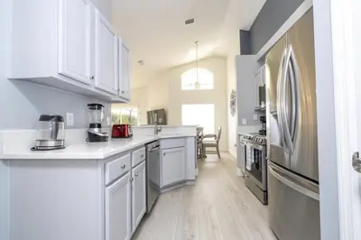 a kitchen with white cabinets and a refrigerator at Sunshine Escape 20 minutes from Disney in Kissimmee