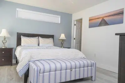 a white bedroom with a bed and a ottoman at Sunshine Escape 20 minutes from Disney in Kissimmee