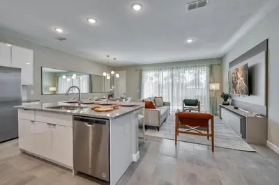 a kitchen with a sink and a living room at Luxuosa Villa 4Q c/ Piscina | 10 min da Disney! in Orlando