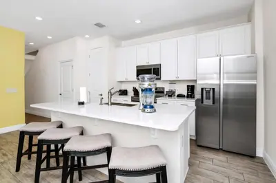 a kitchen with white cabinets and a kitchen island with stools at Coastal Haven Villa Near Disney With Margaritaville Resort & Island H20 Waterpark Access - 2964Or in Orlando