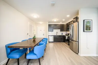 a kitchen and dining room with a wooden table and blue chairs at Epic Universe New Modern Vista Cay Reserve Condo - 5005 in Orlando