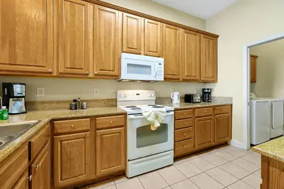 a kitchen with wooden cabinets and a white stove top oven at Living the Disney Dream! Lake View Luxury Condo in Orlando
