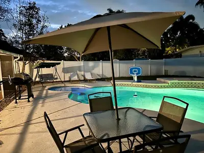 a table and chairs with an umbrella next to a swimming pool at Orlando Luxe Retreat with Private Pool in Orlando
