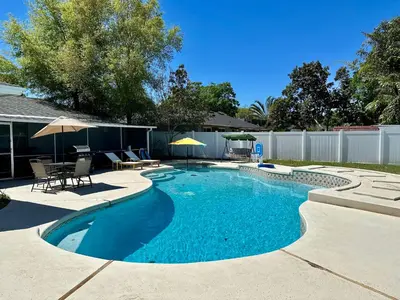 a swimming pool with chairs and umbrellas in a yard at Orlando Luxe Retreat with Private Pool in Orlando